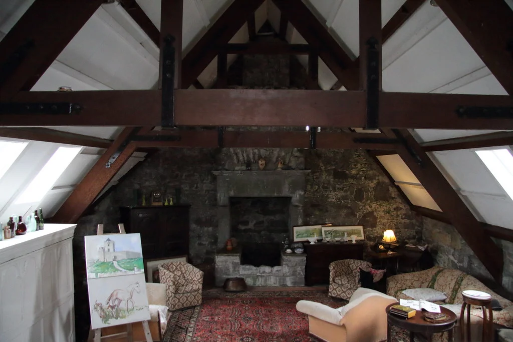 The beautiful cozy attic with chimney, paintings and sofa seats in Dunguaire Castle.