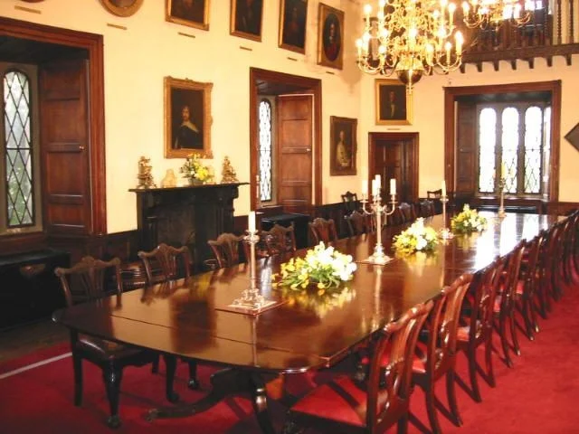 Malahide Castle's beautiful great hall with hanging portraits and chandelier.