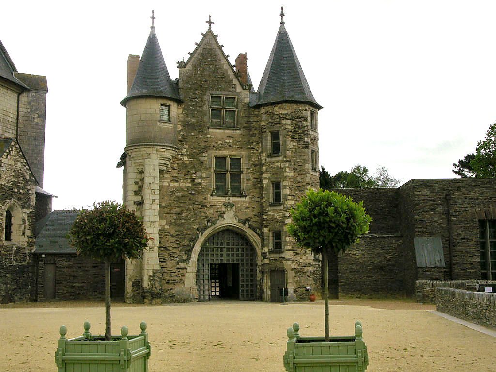 The front gateway of Chateau d'Angers with two trees in the foreground.