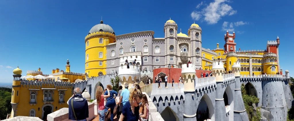 https://www.revisitinghistory.com/wp-content/uploads/2021/10/pena-palace-surrounding-with-tourists-1024x422.jpg.webp