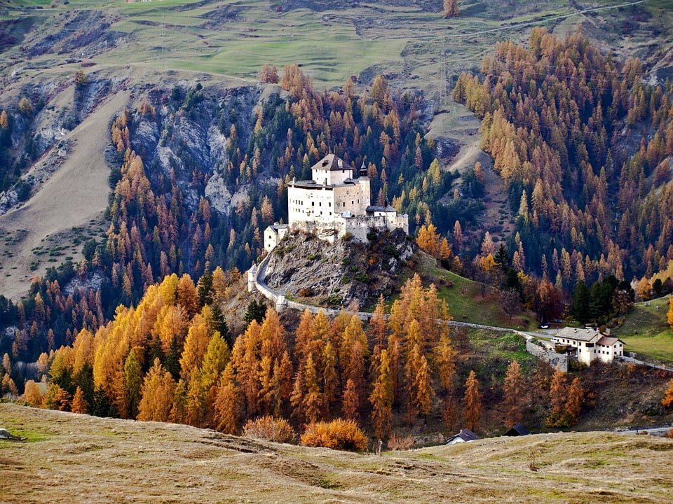 The picturesque view of Tarasp castle surrounded by trees.